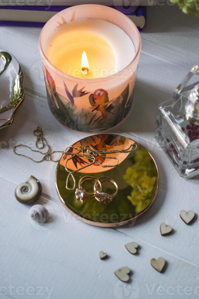 Candle, perfume bottle and jewels on a white table. photo