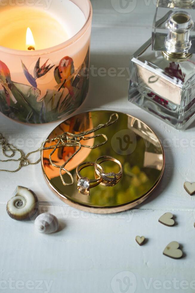 Candle, perfume bottle and jewels on a white table. photo