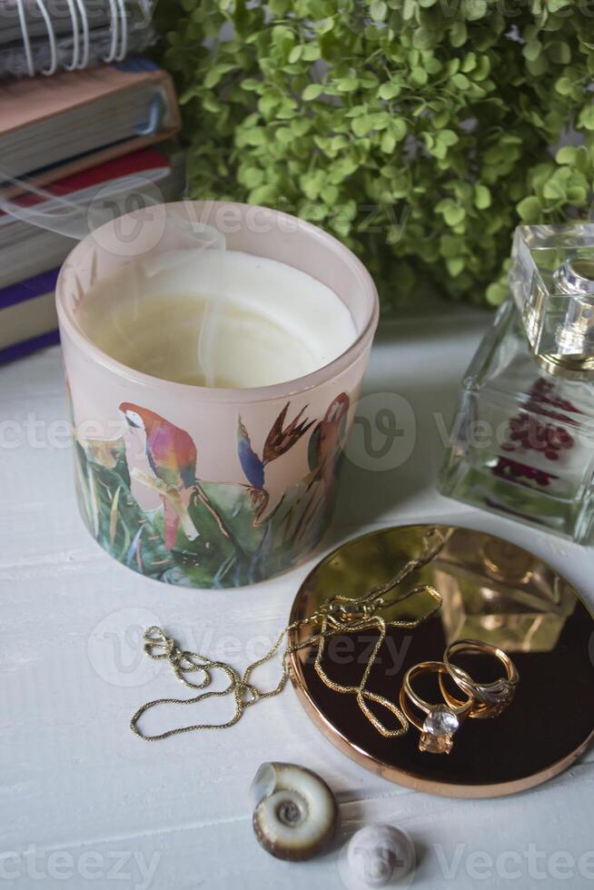 Candle, perfume bottle and jewels on a white table. photo