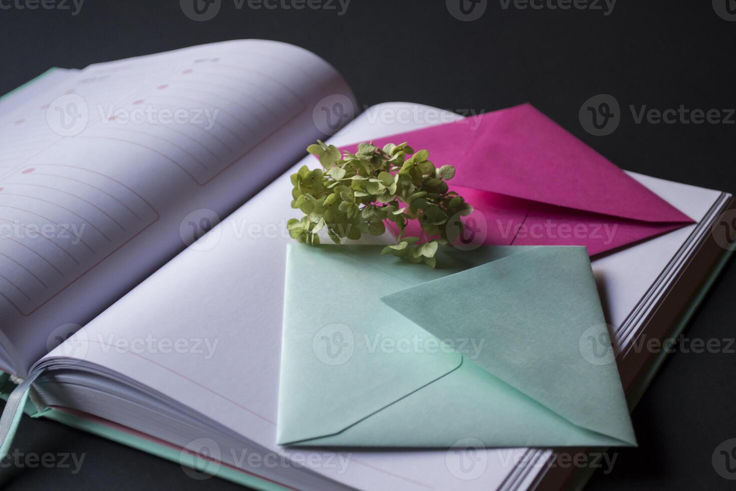 The turquoise and pink colors envelopes on the opened notepad, close up. photo
