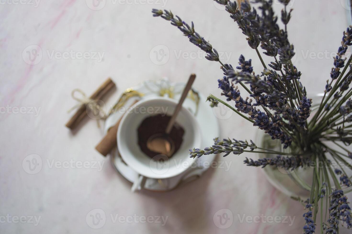 A cup of coffee with cinnamon and lavender flower on a table. photo
