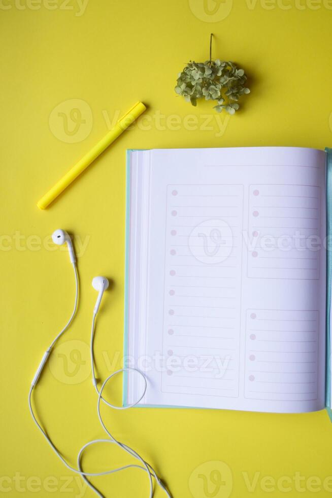 Opened planner with decor on a yellow background. Modern workplace. photo