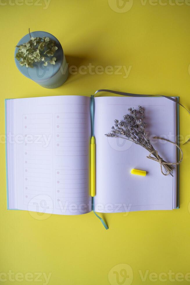 Opened planner with decor on a yellow background. Modern workplace. photo