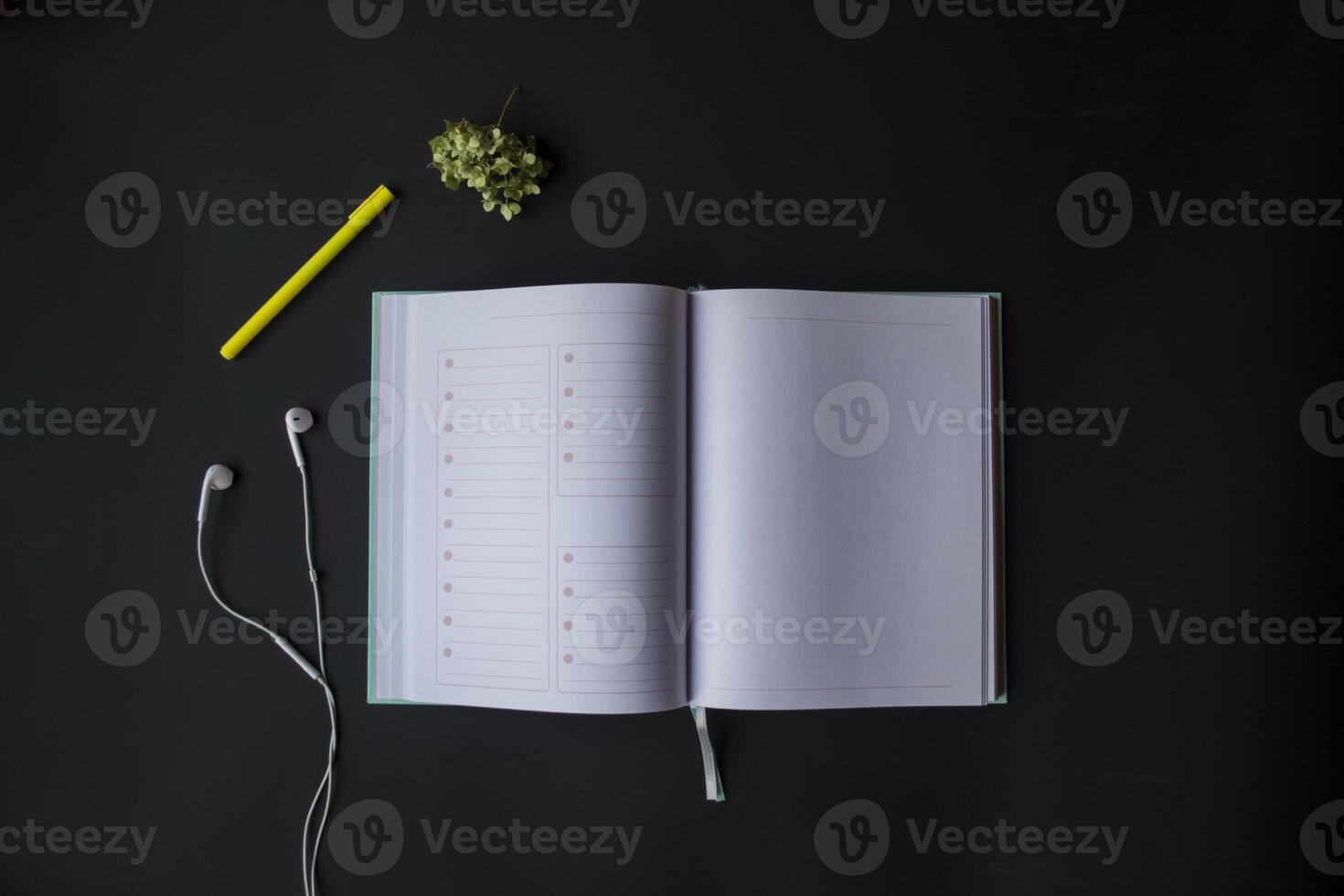 Opened planner with pen and head phones on the black table. Modern workplace. Background with copy space. photo