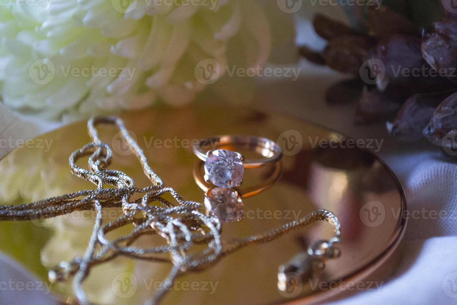 The golden chain and ring with diamond near flower, close up. photo