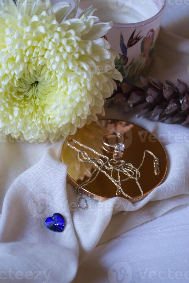 The golden chain and ring with diamond near flower, close up. photo