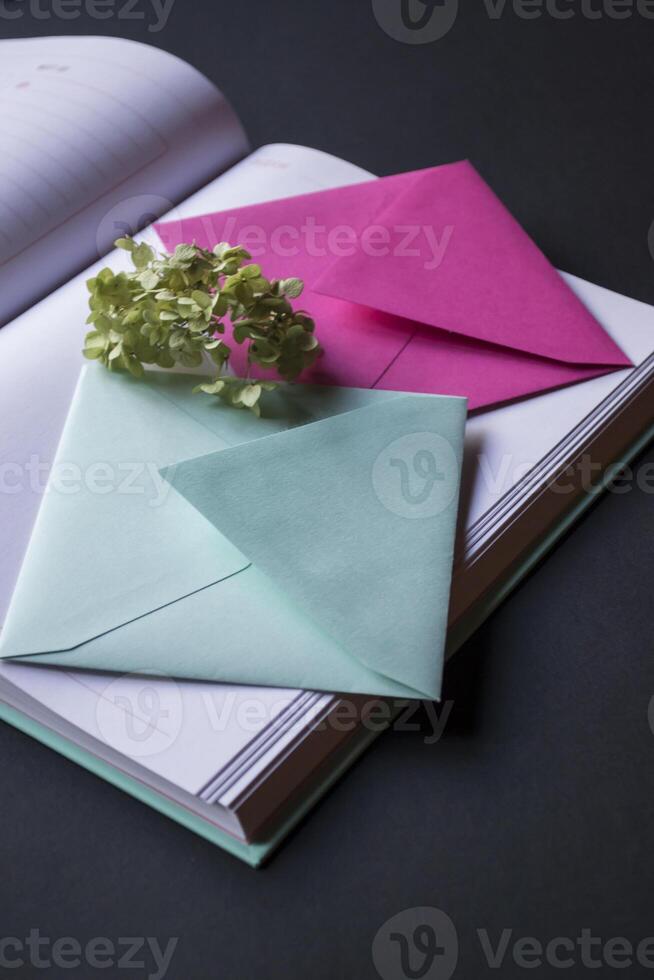 The turquoise and pink colors envelopes on the opened notepad, close up. photo
