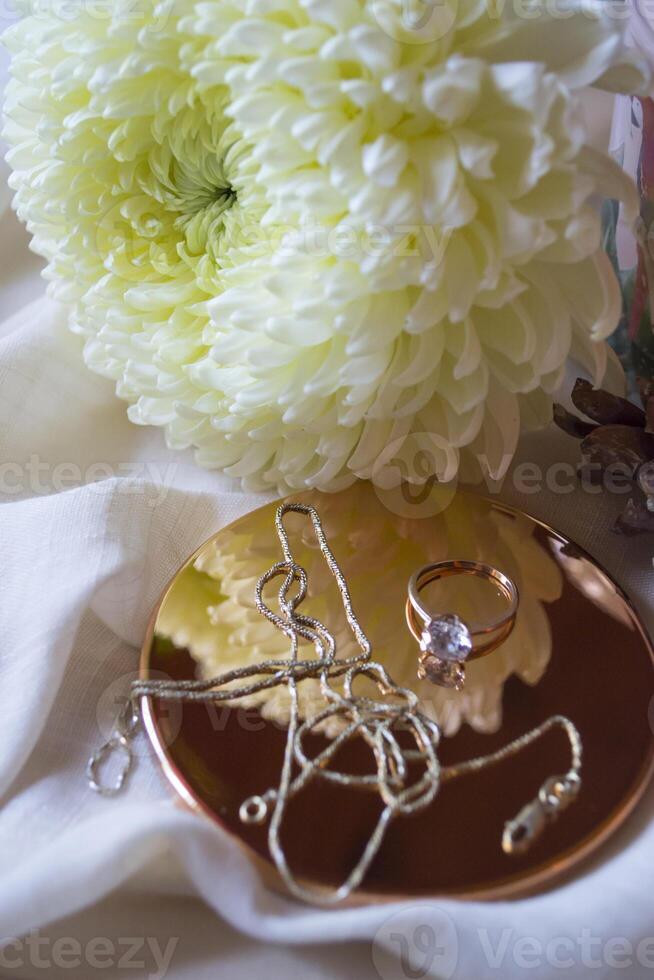 The golden chain and ring with diamond near flower, close up. photo