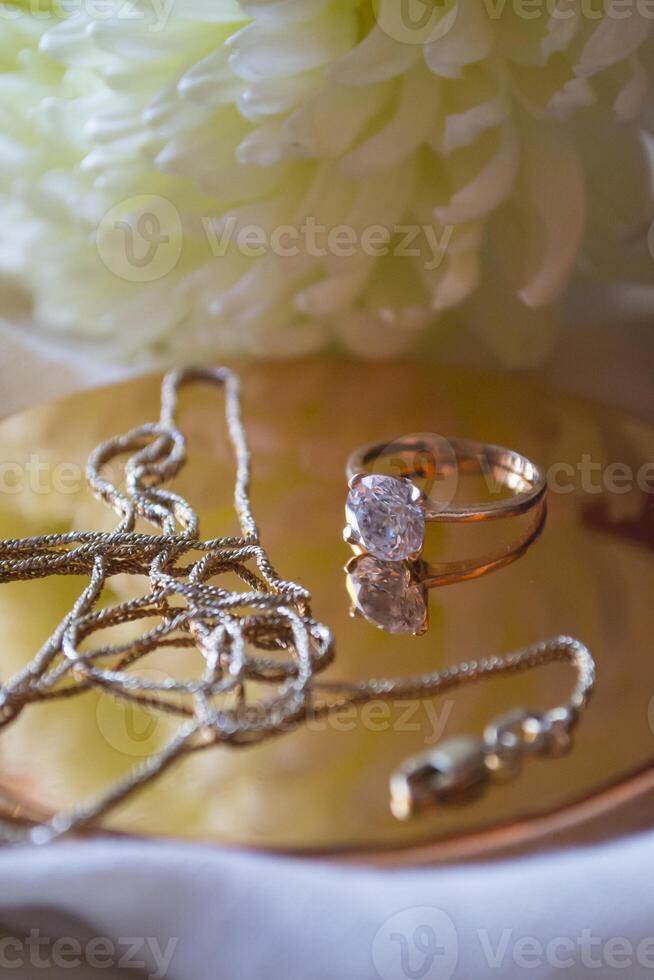 The golden chain and ring with diamond near flower, close up. photo