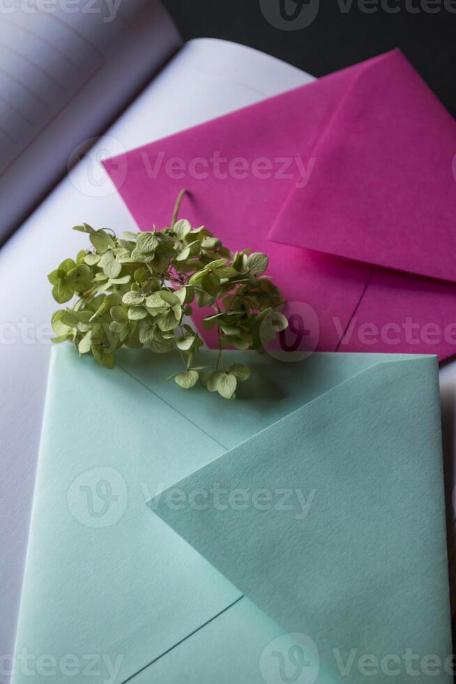 The turquoise and pink colors envelopes on the opened notepad, close up. photo