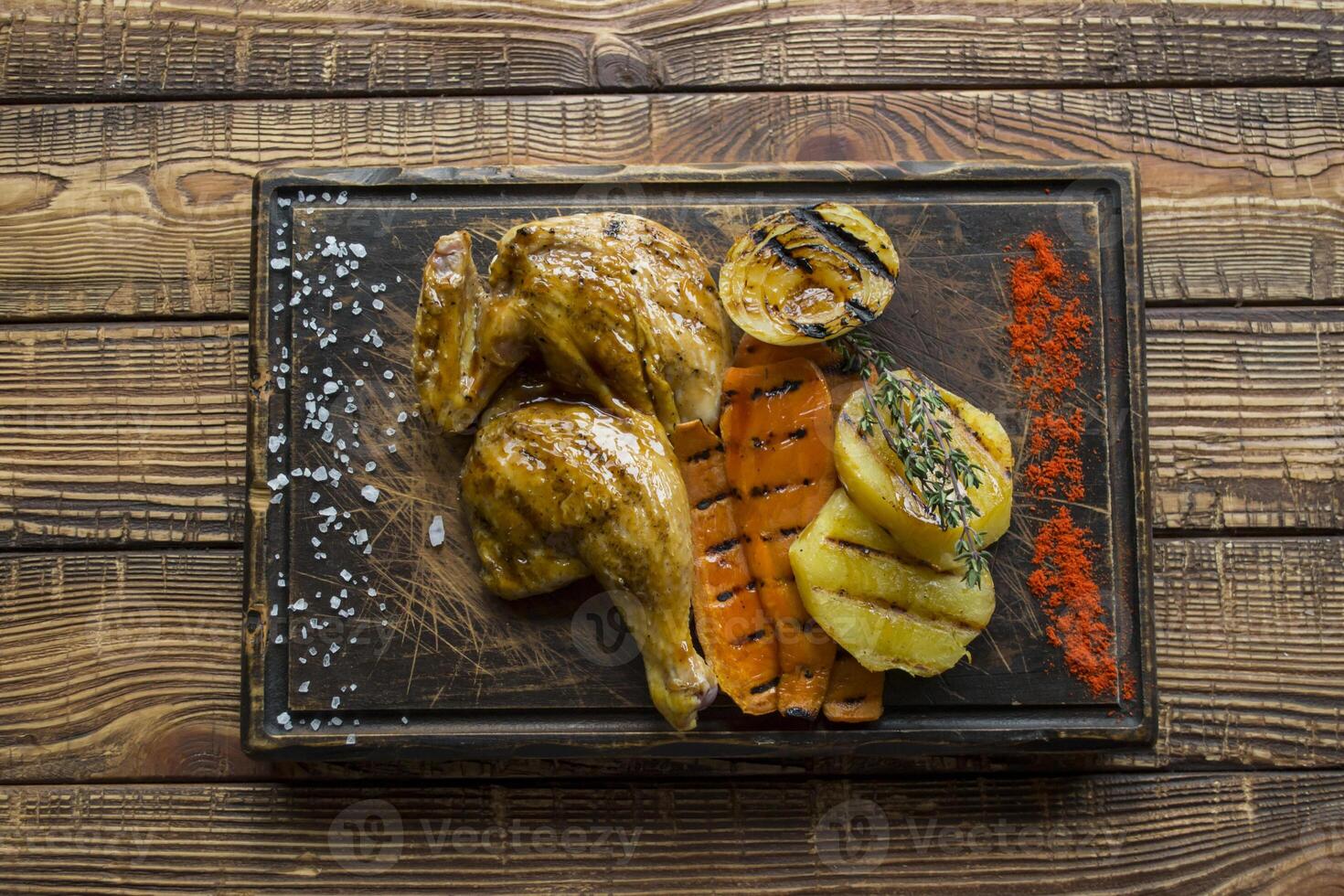 Grilled chicken and vegetables on a wooden table. photo