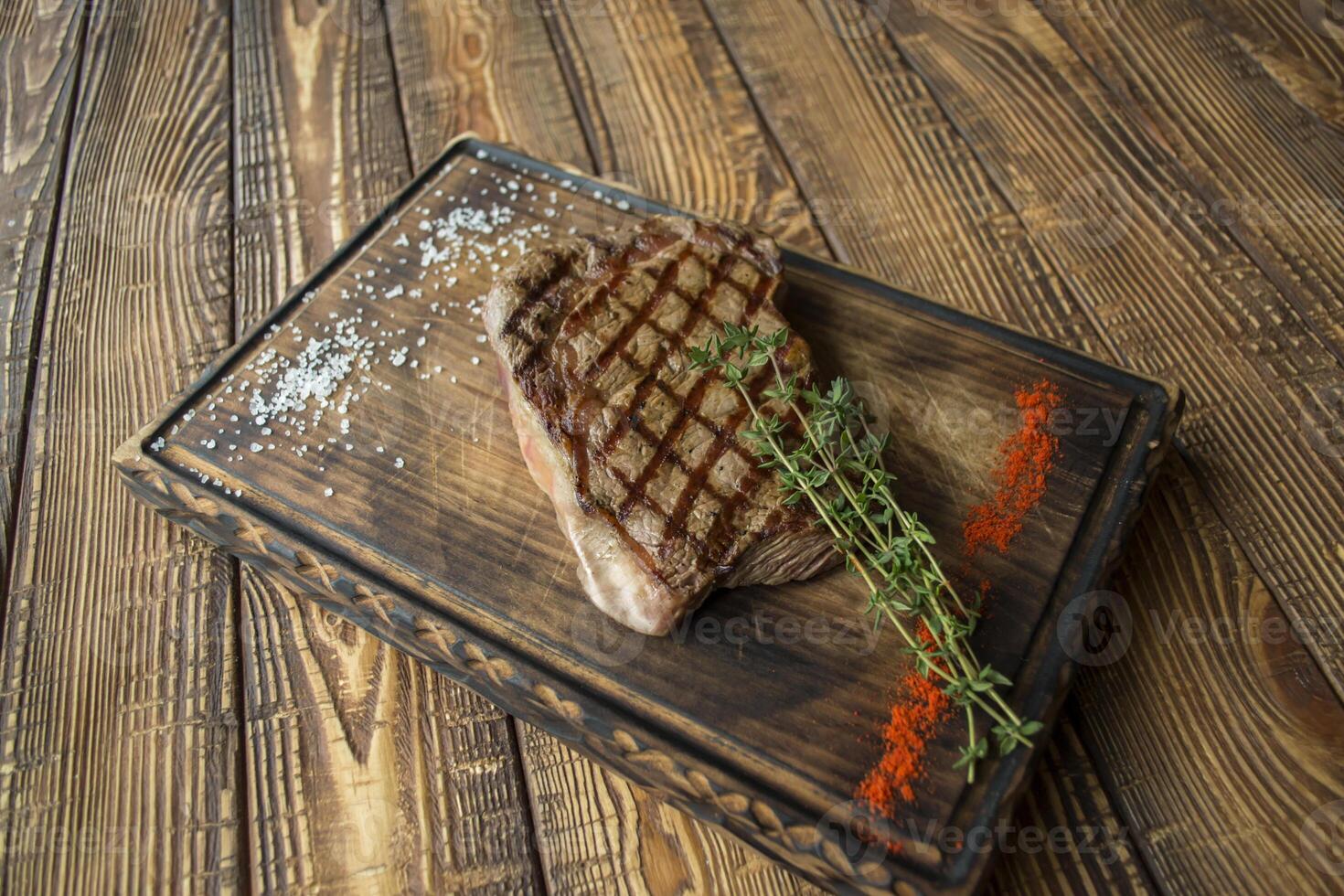 Grilled meat with sauce and rosemary on a wooden table. photo