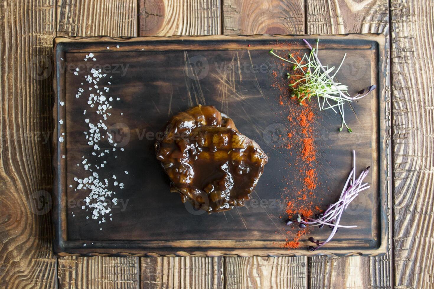 Grilled meat with spices and sauce on a wooden table. photo