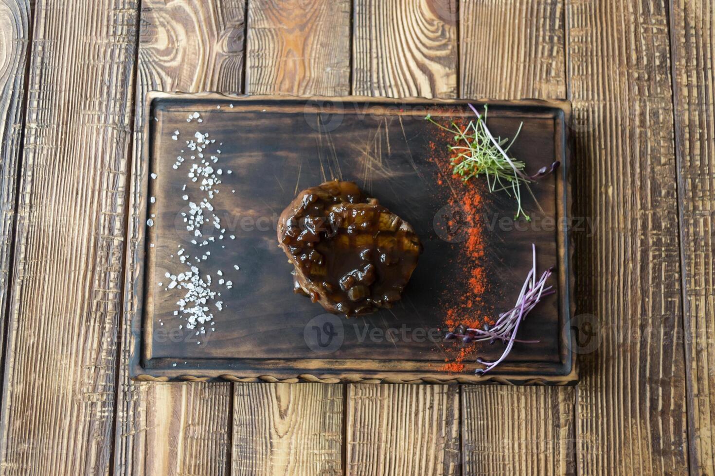 Grilled meat with spices and sauce on a wooden table. photo