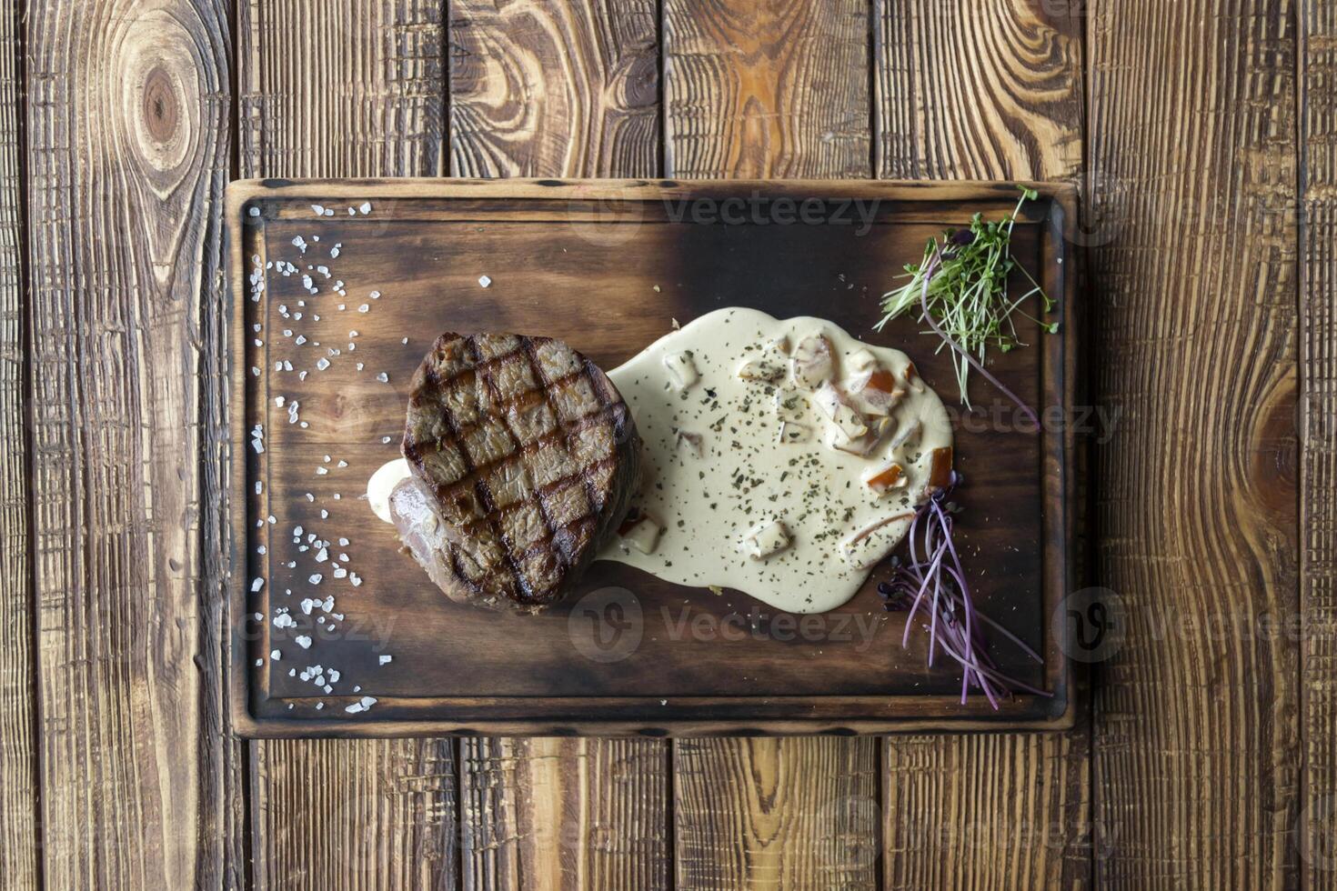 Grilled meat with spices and sauce on a wooden table. photo