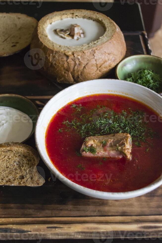 Borscht with sour cream on a wooden table. photo