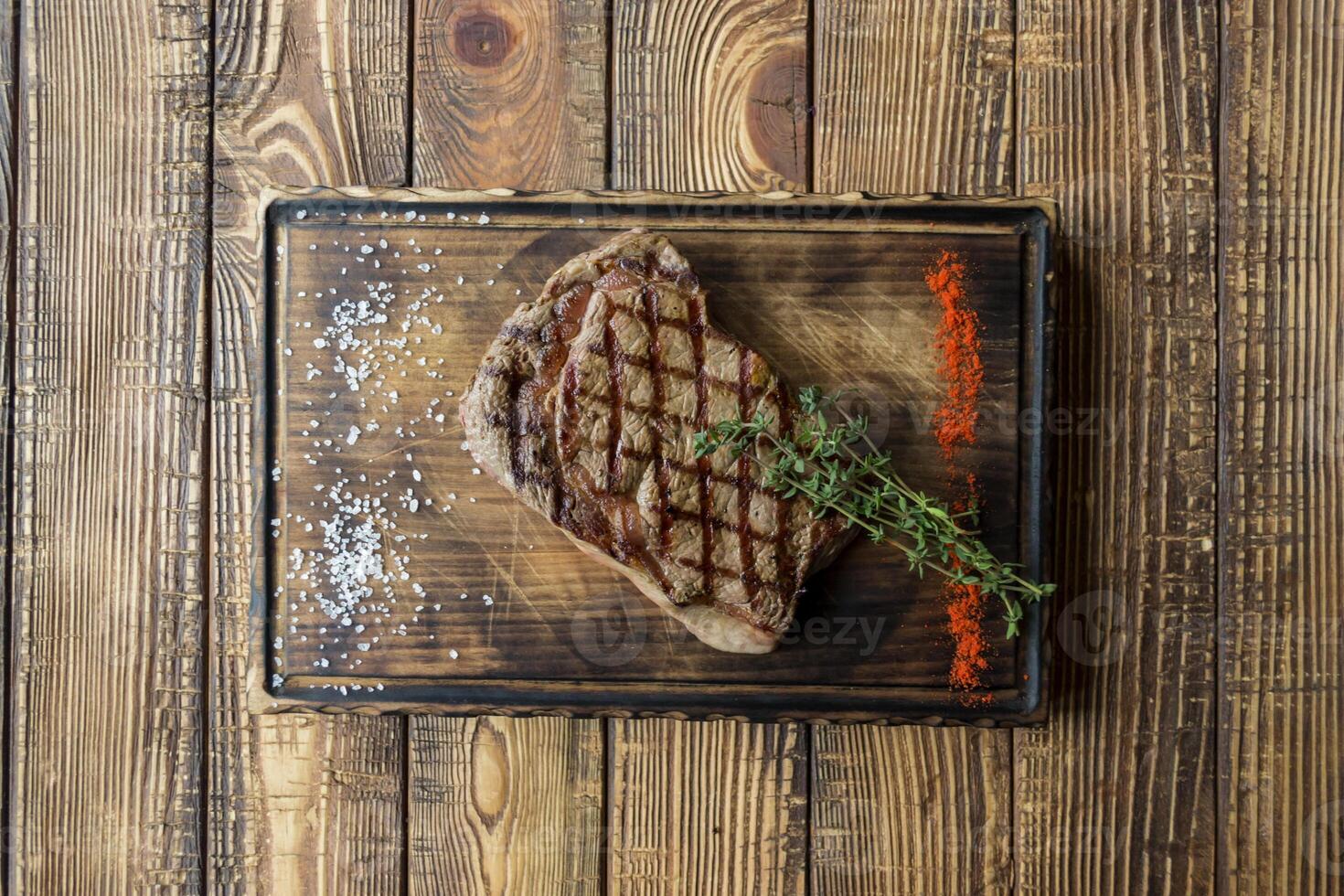 Grilled meat with sauce and rosemary on a wooden table. photo