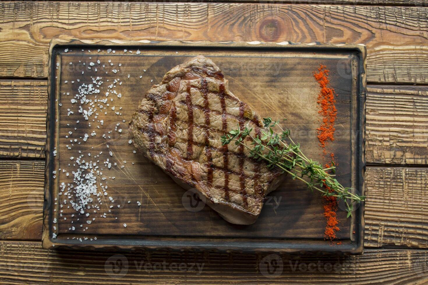 Grilled meat with sauce and rosemary on a wooden table. photo