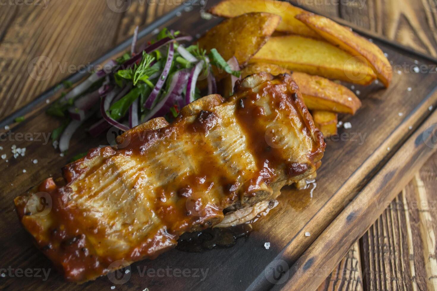 Fried potatoes with grilled meat on a wooden table. photo