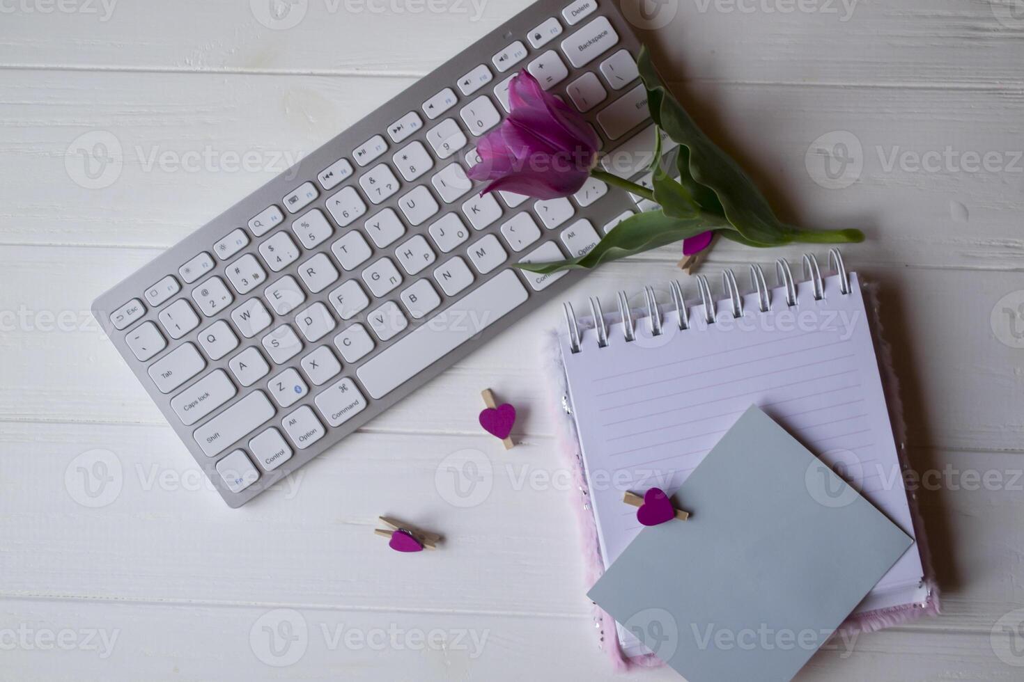 Computer keyboard and notebook with empty sheet. Modern workplace. photo