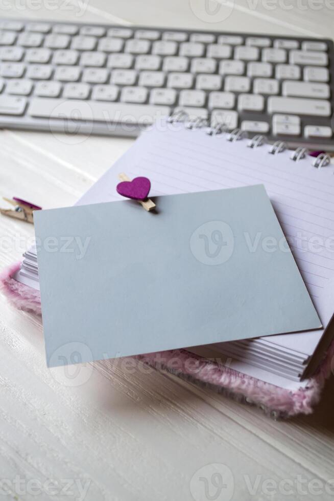 Computer keyboard and notebook with empty sheet. Modern workplace. photo