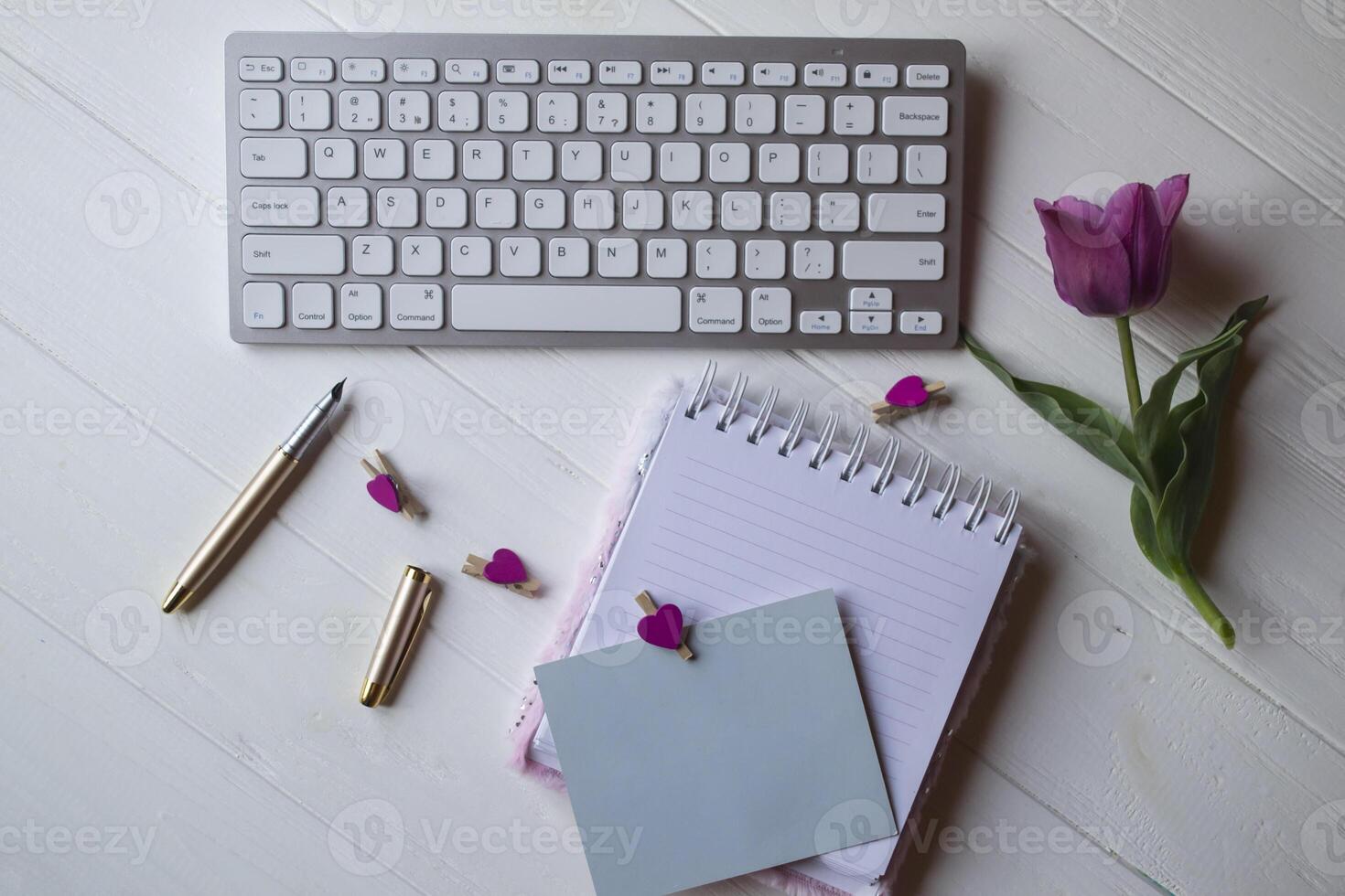 Computer keyboard and notebook with empty sheet. Modern workplace. photo