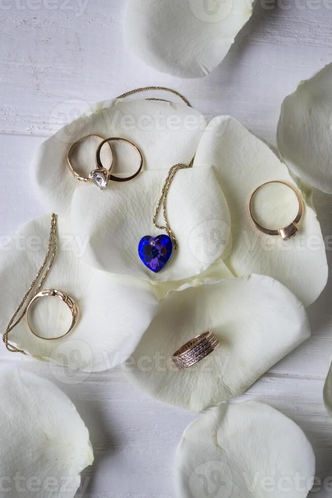 Necklace and gold rings on a white petals of roses. photo