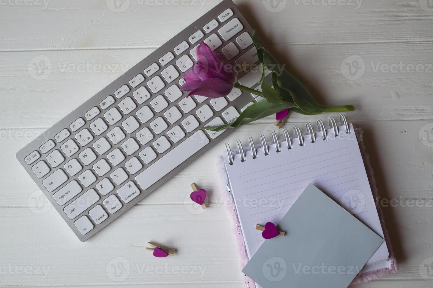Computer keyboard and notebook with empty sheet. Modern workplace. photo