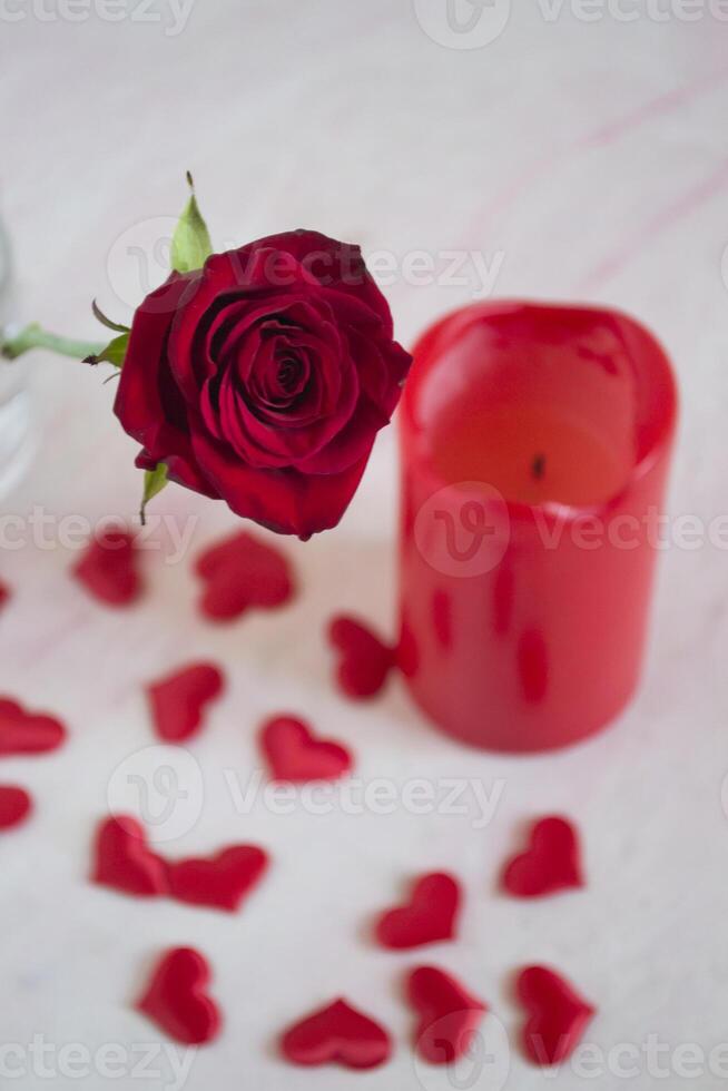 Red rose, hearts and candle on a table. photo
