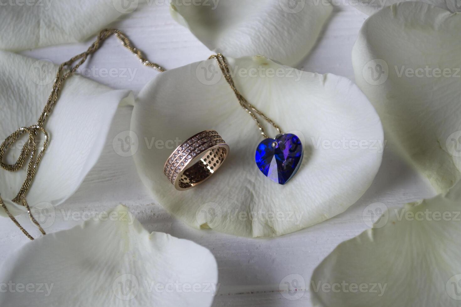 Necklace and gold rings on a white petals of roses. photo