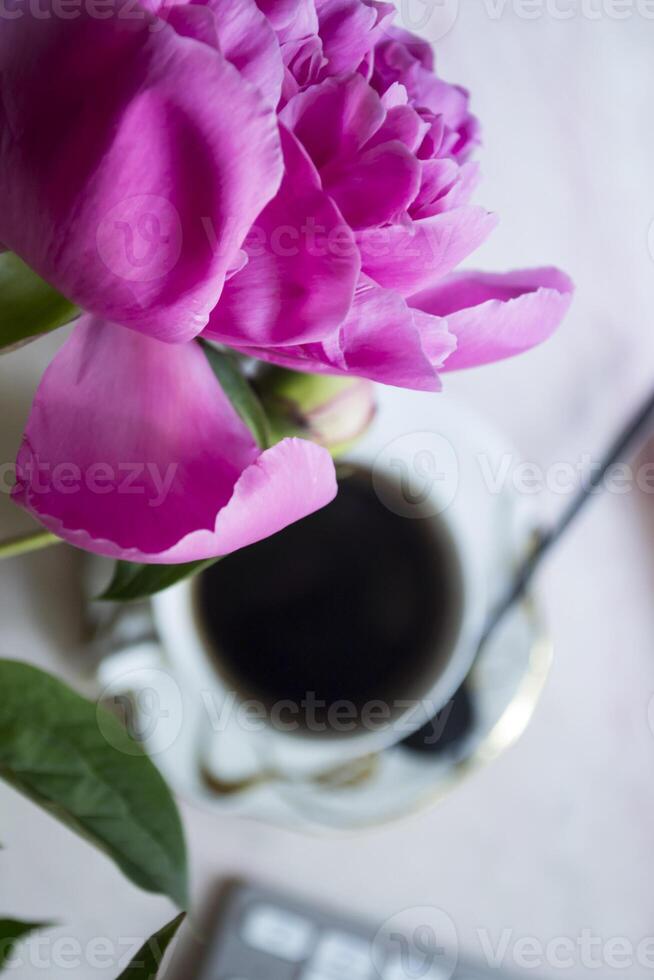 Beautiful workplace with coffee and peony. photo