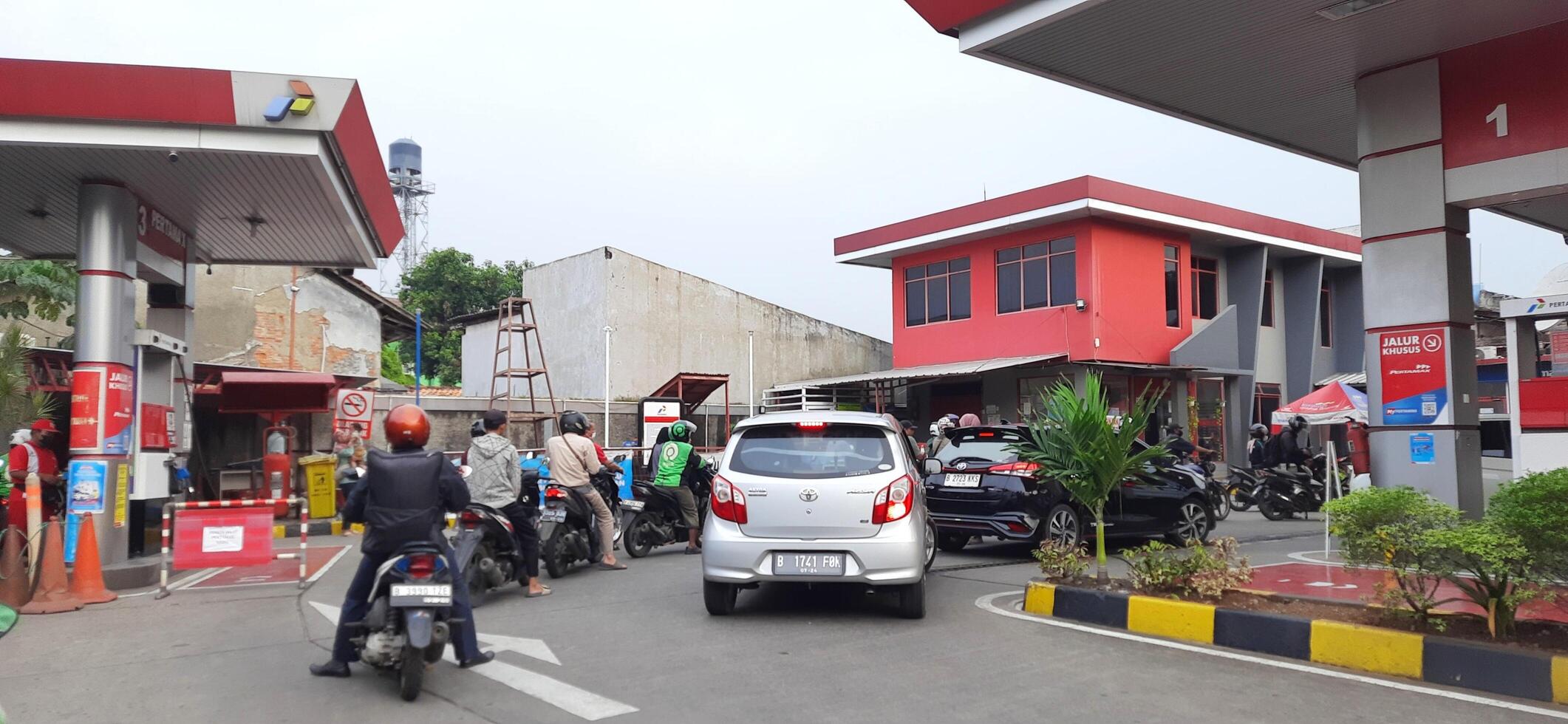 Queue of vehicles public refueling at Pertamina gas station or Pom Bensin during the day. Bekasi, West Java, Indonesia - April 4 2024 photo