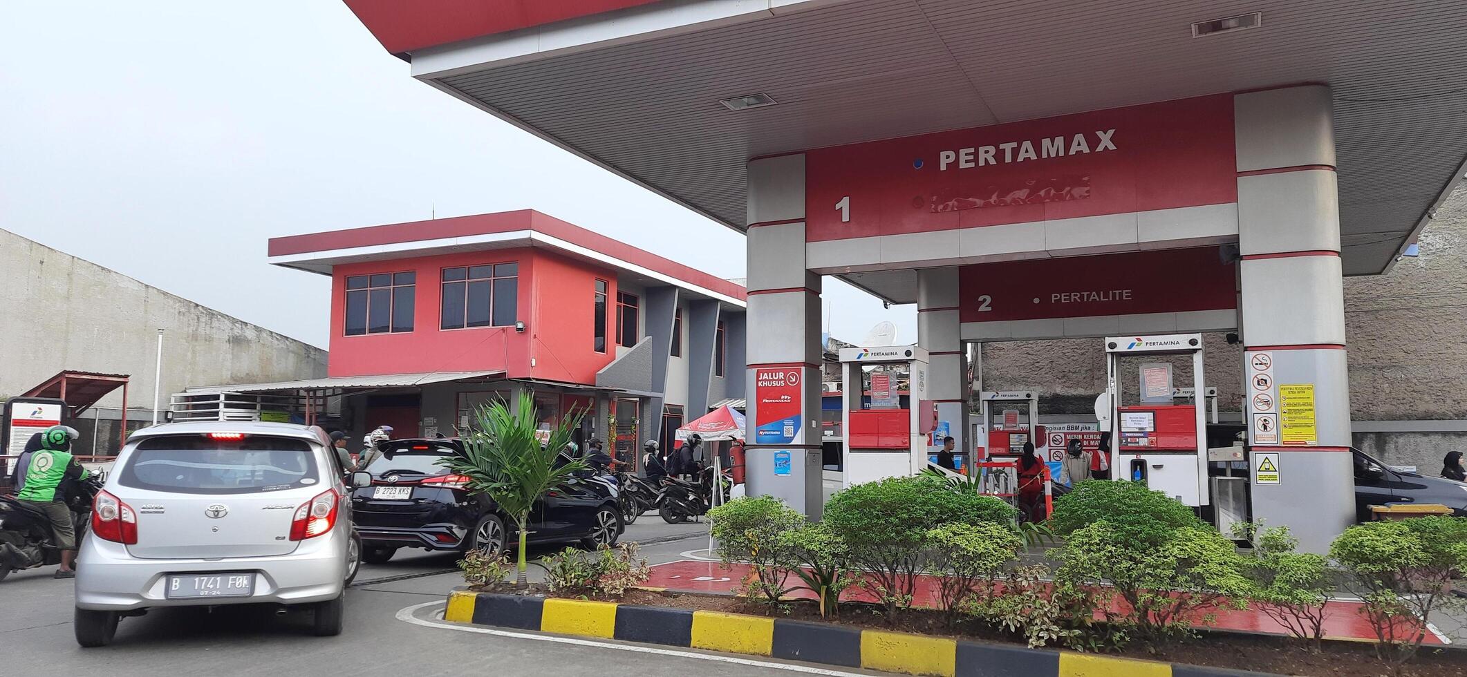 Queue of vehicles public refueling at Pertamina gas station or Pom Bensin during the day. Bekasi, West Java, Indonesia - April 4 2024 photo