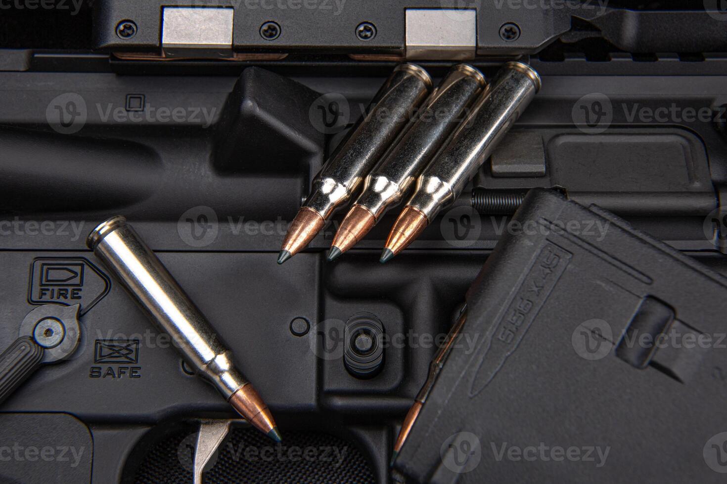 Close-up of .223 carbine cartridges. Loaded weapon clip. Weapons in the back photo