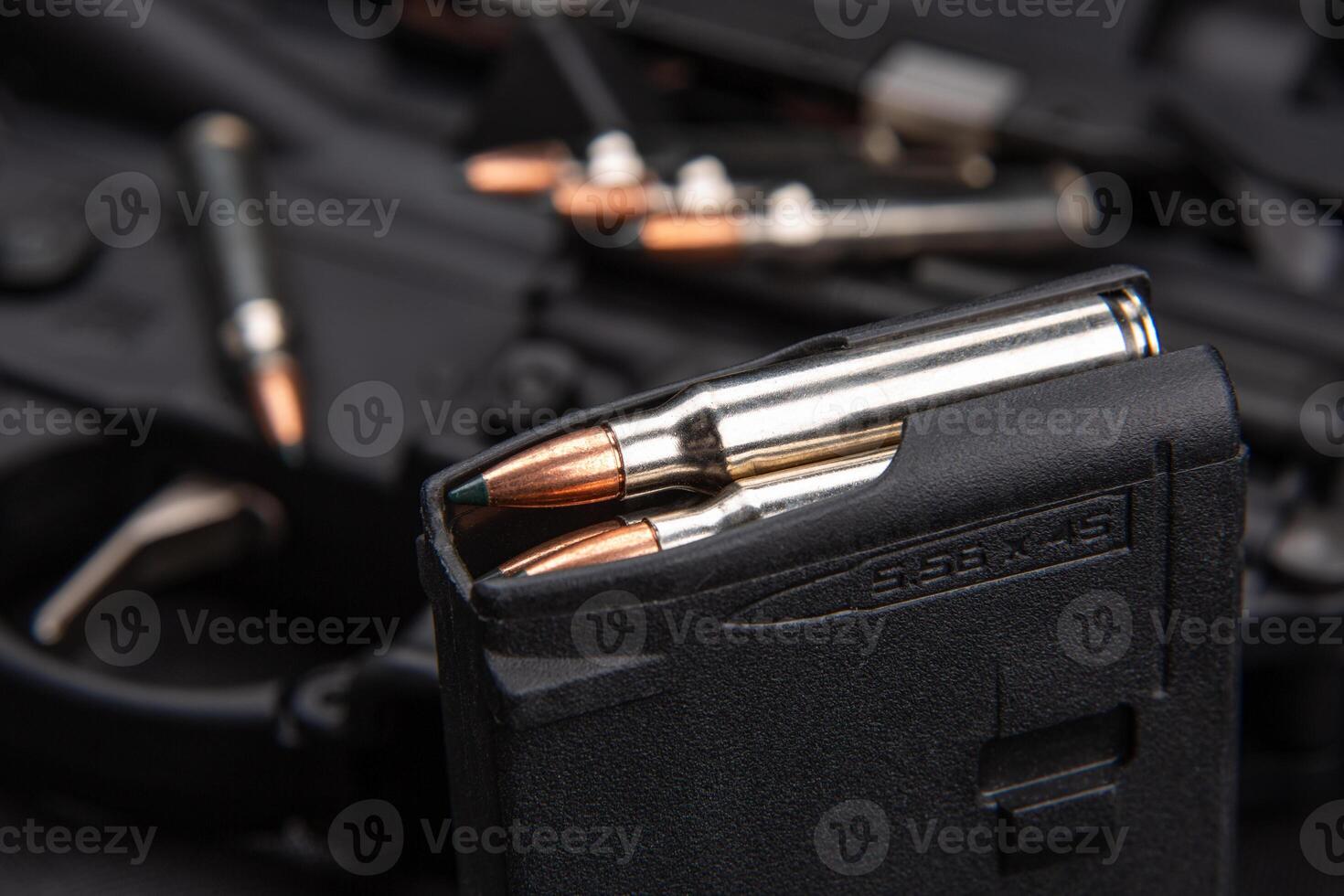 Close-up of .223 carbine cartridges. Loaded weapon clip. Weapons in the back photo