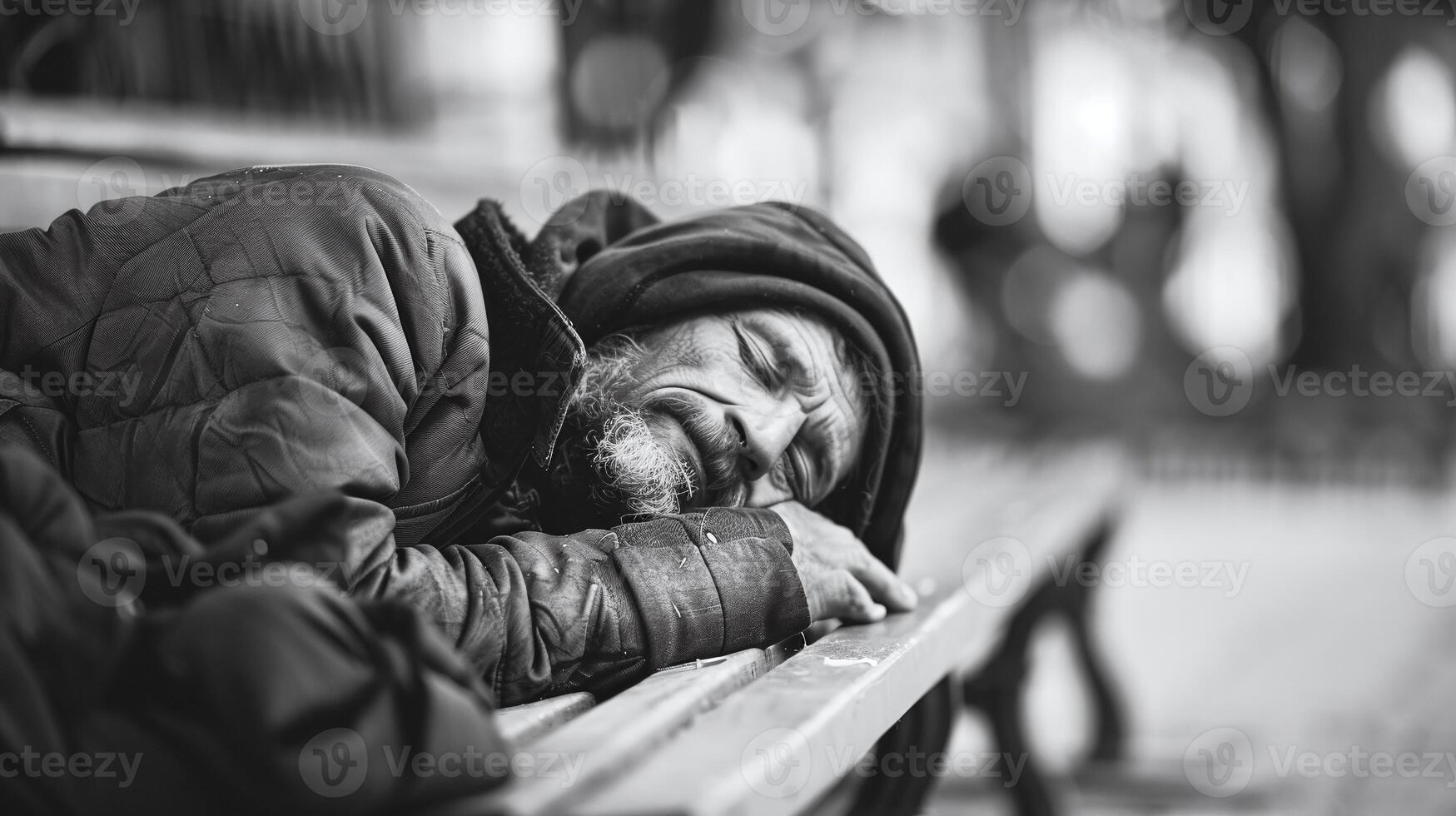 Emotive black and white photo of a bearded homeless man resting on a bench, highlighting social issues and urban struggle