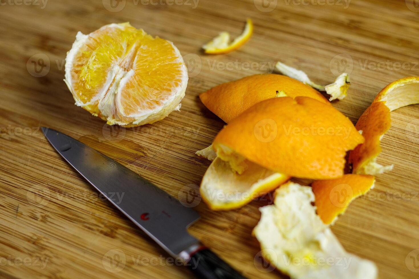 Orange peeled and cut on wooden cutting board with peel and japanese knife photo