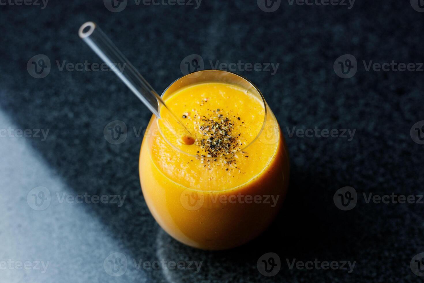 mango Zanahoria manzana zalamero en un vaso en oscuro antecedentes con vaso Paja foto