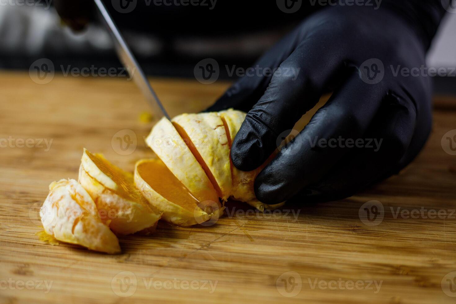 persona con negro guantes cortes pelado naranja en de madera corte tablero dentro piezas foto