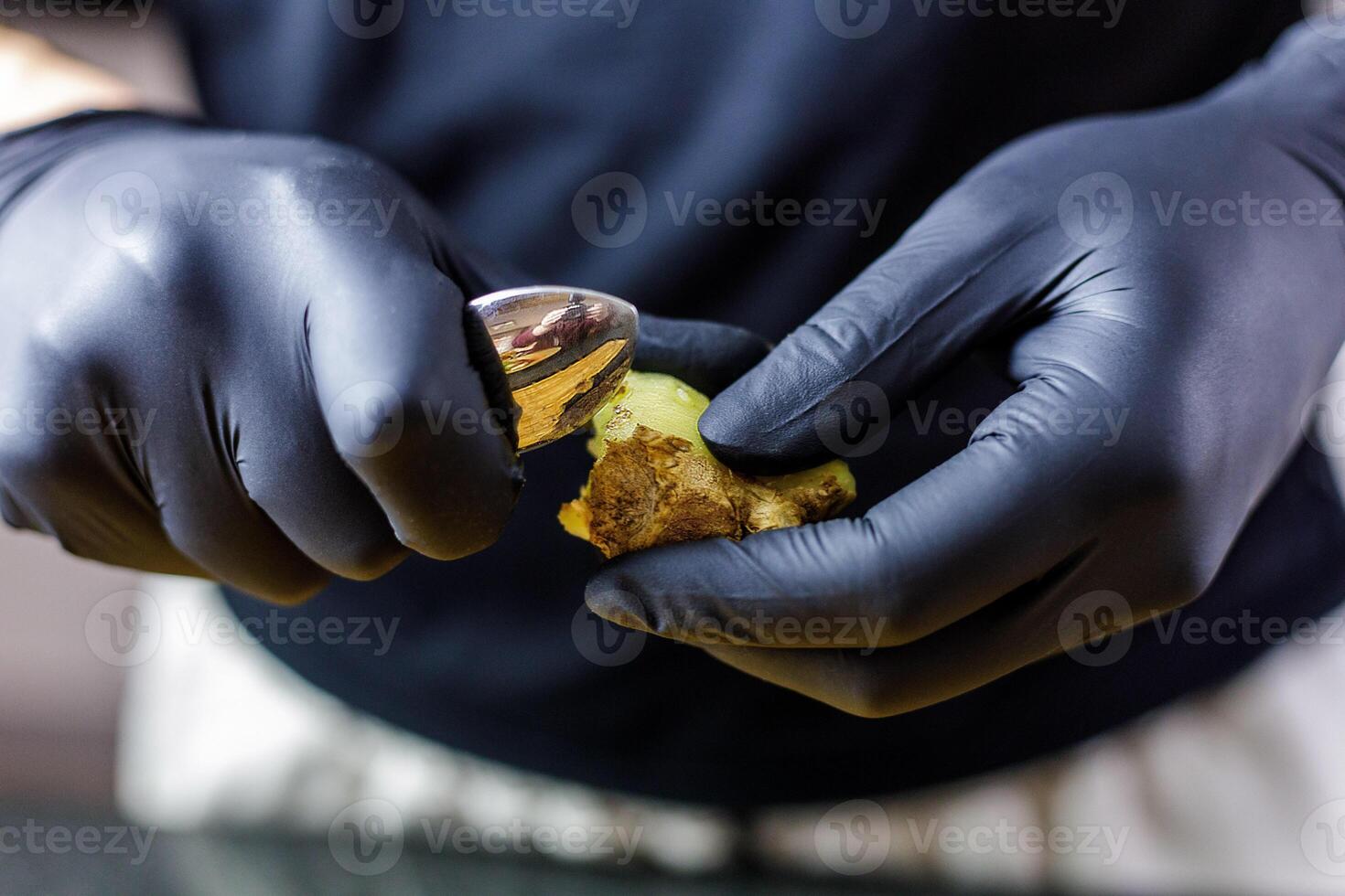 Person with black gloves Peeles and cuts ginger photo