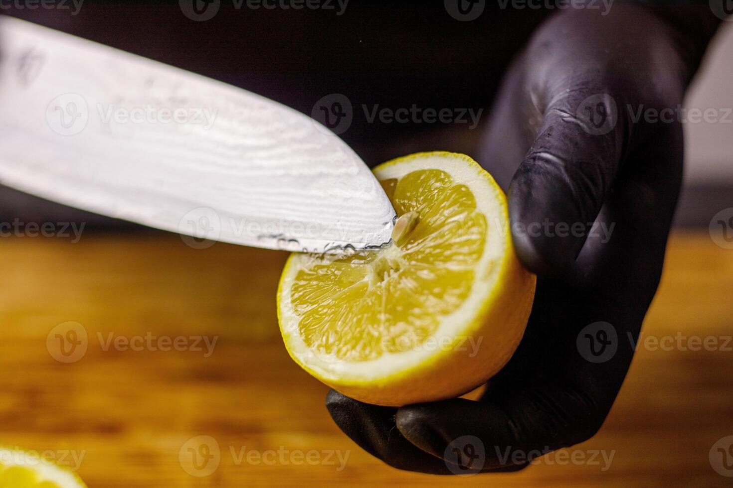 Person with black gloves cutting lemon in half photo