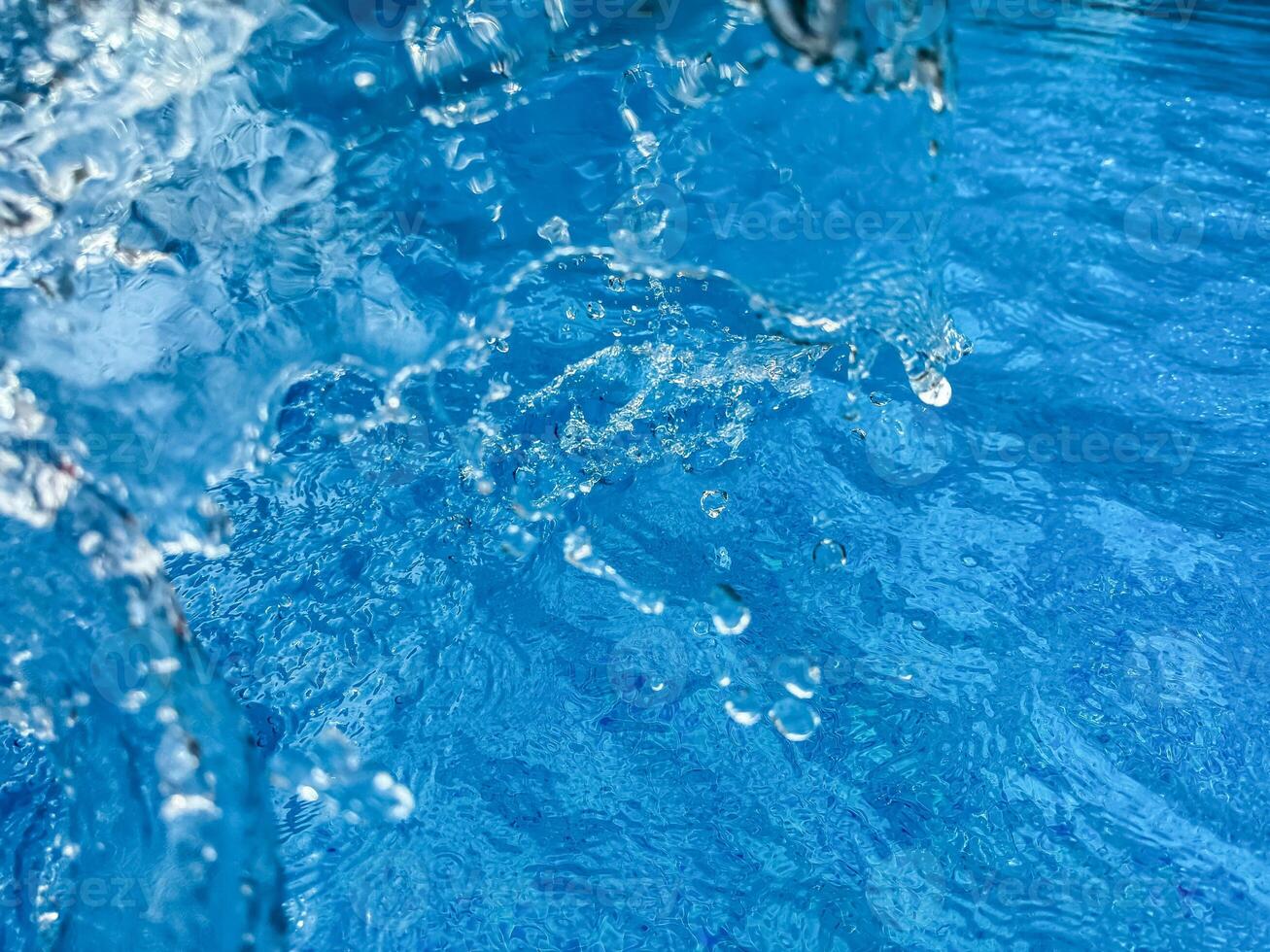 Background dynamic splash of clear water creating swirling wave in blue water with droplets suspended in motion. Clean water concept. photo