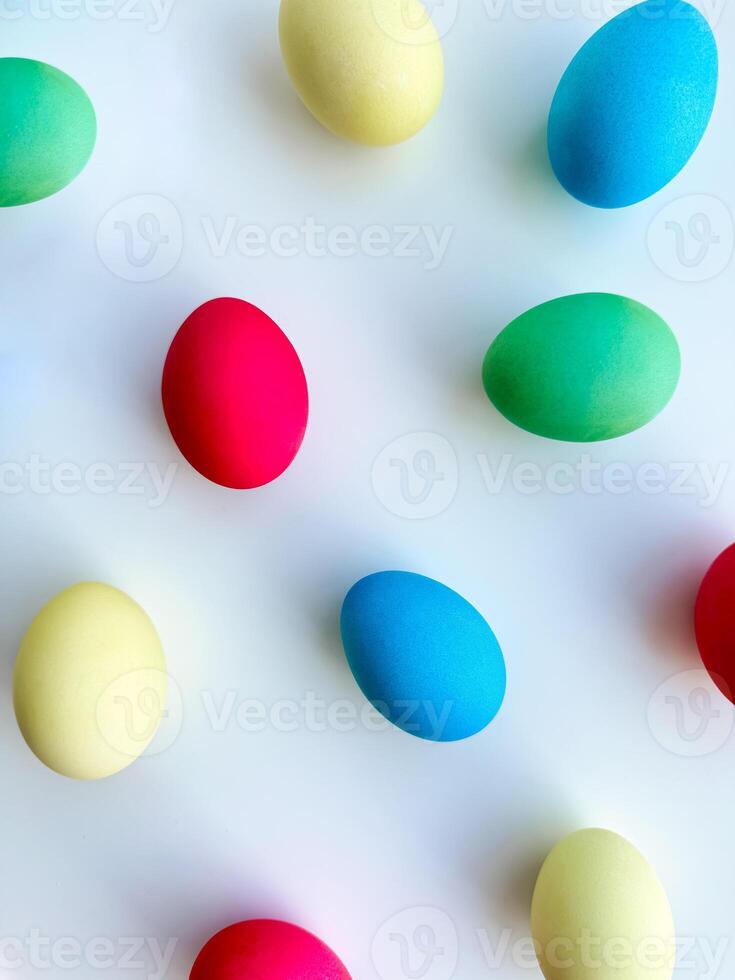 Colorful Easter eggs scattered on white background, flat lay composition for spring holiday celebration and decoration ideas. For Easter holiday promotions, themed party invitations, seasonal blog photo