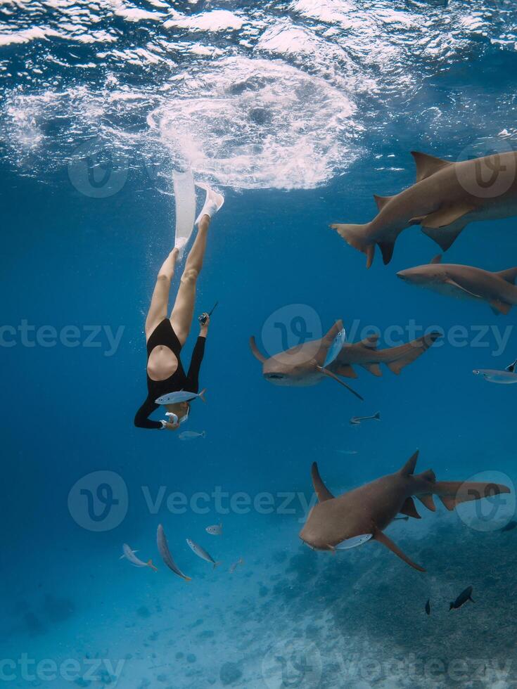 mujer inmersiones con tiburones en un tropical mar en el Maldivas. gratis buceo con enfermero tiburones foto