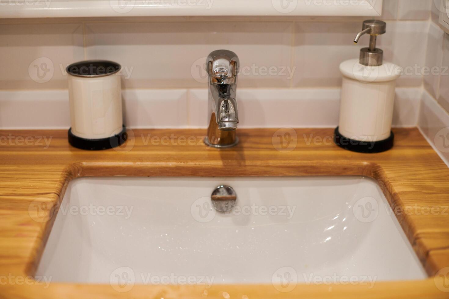 Faucet in sink with wooden countertop photo