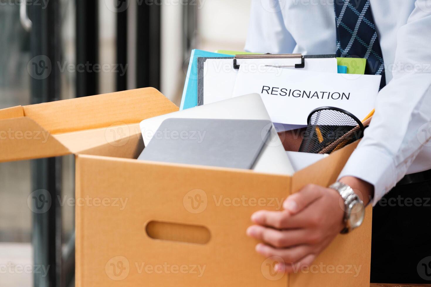 Man places personal items and resignation letter into a box, ending his tenure. photo
