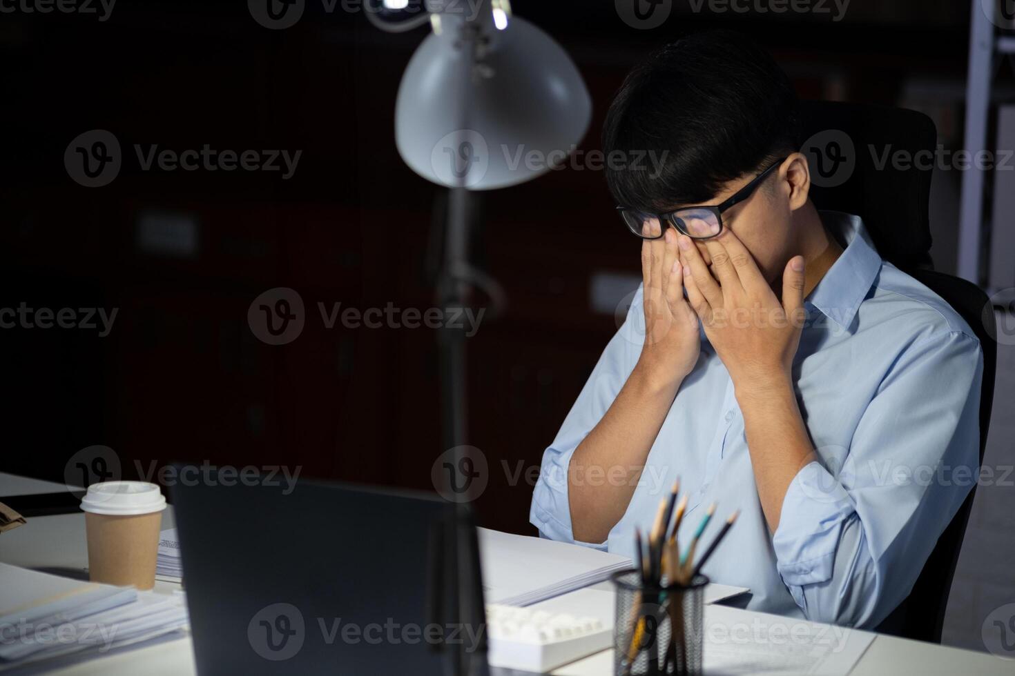 Businessman working overtime at his office makes his eyes tired. photo