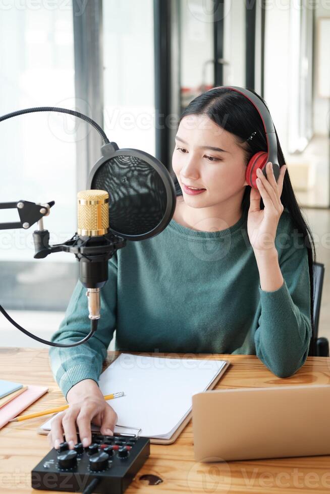 A woman is sitting at a desk with a microphone and a laptop photo