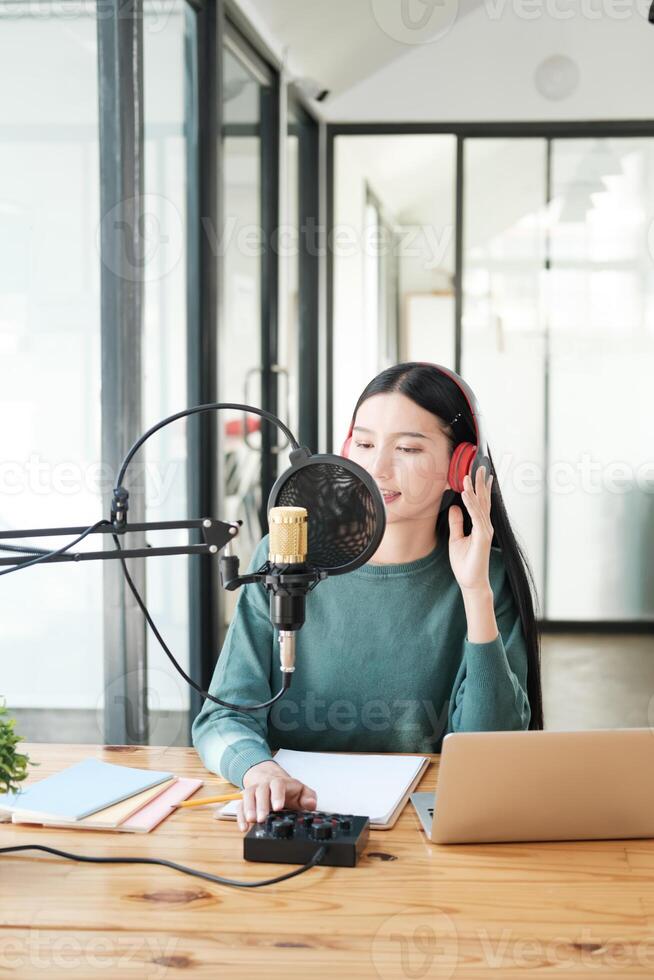 A woman is sitting at a desk with a microphone and a laptop photo