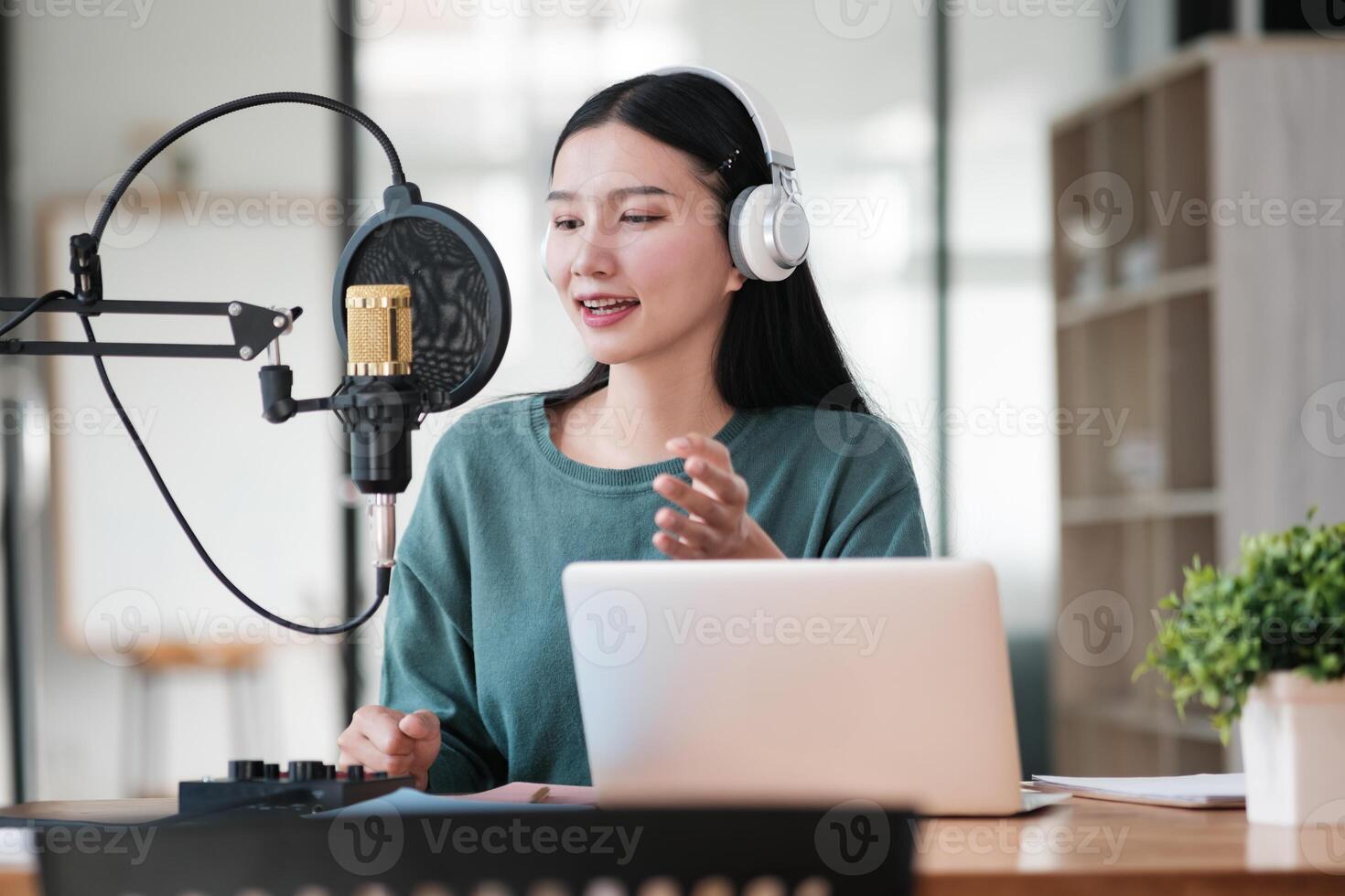 A woman is sitting at a desk with a laptop and a microphone photo